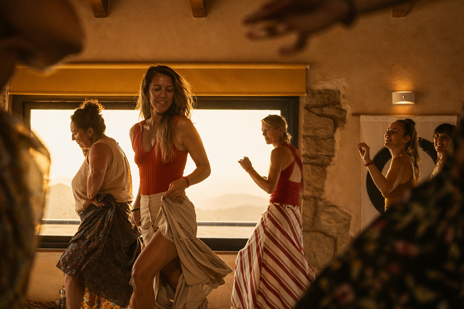 Grupo de mujeres danzando frente a una ventana al atardecer